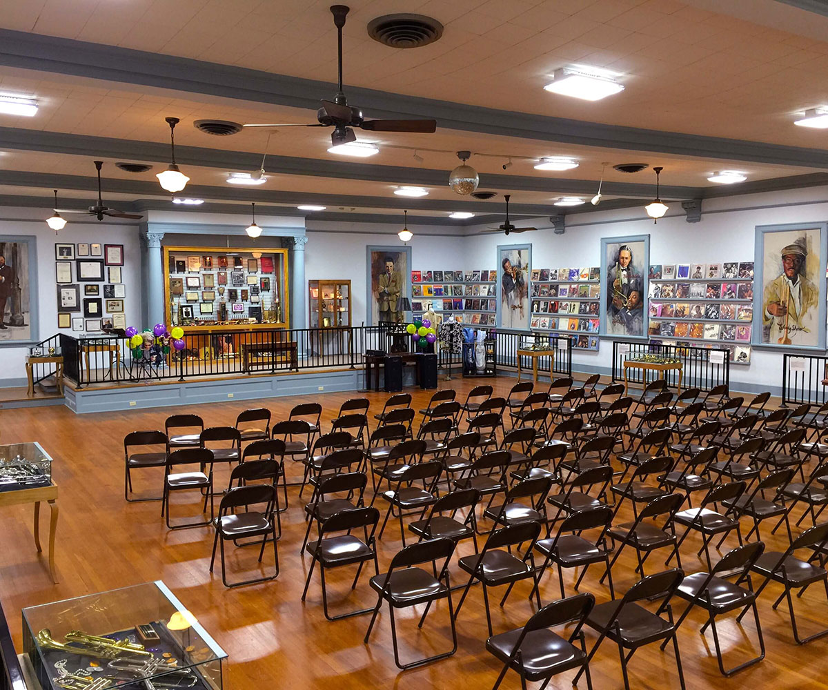 Image of a large room with folding chair seating, and a stage.