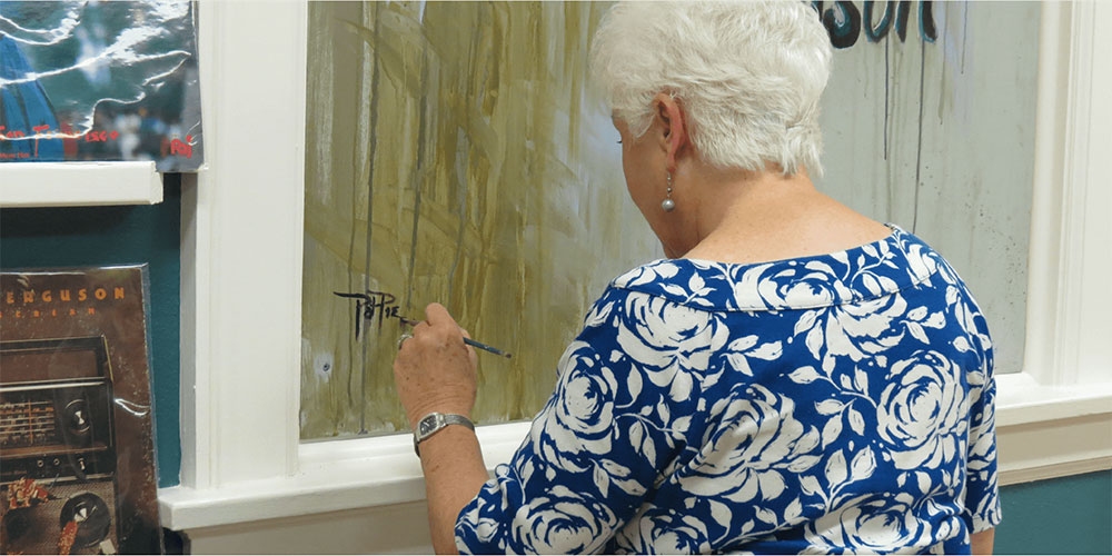 Photo of Pat Pierce signing a mural she painted