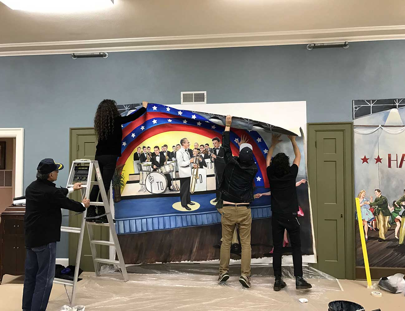 A photo of three people hanging up a printed mural