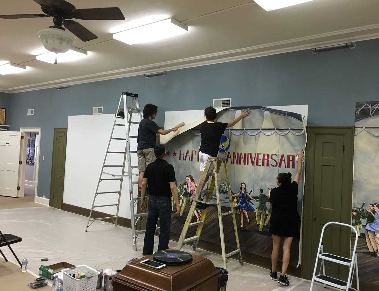 A photo of four people hanging up a printed mural